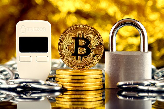 Hardware Wallet: Trezor One di dekat tumpukan Bitcoin.