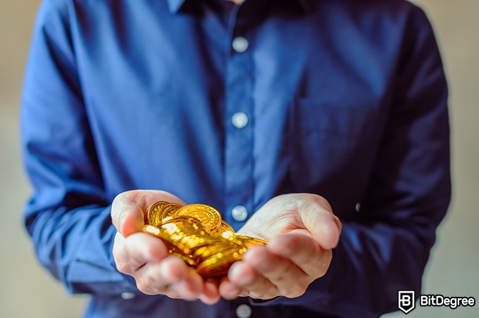 Best time ot buy Bitcoins: a man holding some physical Bitcoins.