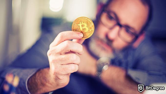 Qué es Bitcoin: Hombre sosteniendo una moneda Bitcoin.