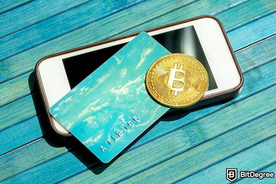 Buy gift cards with crypto: a physical Bitcoin and a card are placed on top of a phone.