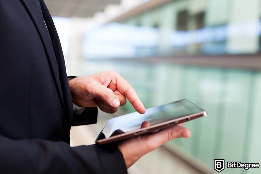 Coinbase Earn: A man tapping a tablet screen.