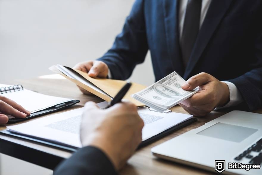 Crypto winter meaning: a man taking out money from an envelope, in a meeting.