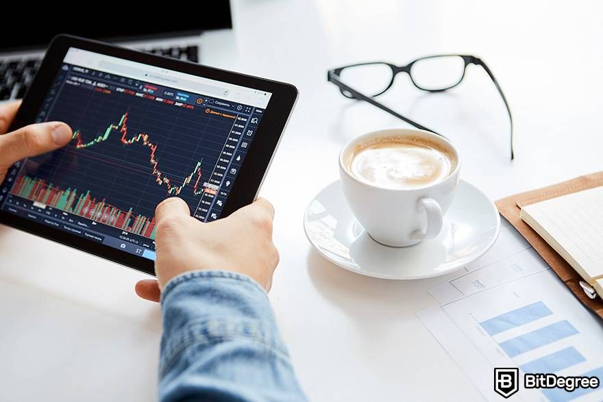 How to invest in crypto: a man is holding a tablet that's displaying market charts.