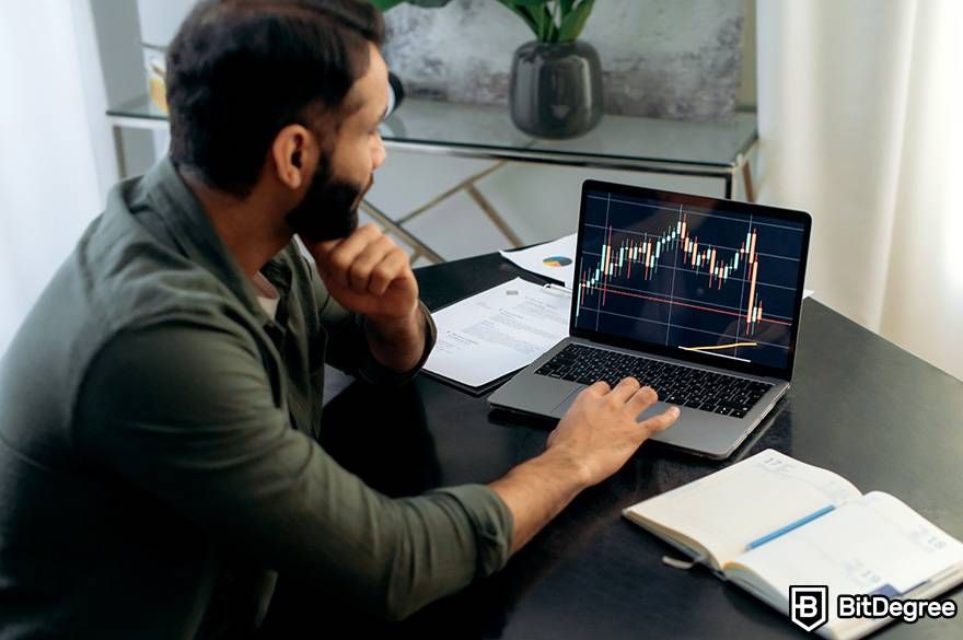 How to invest in crypto: a man is looking at a laptop that displays market volume.