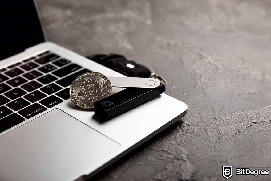 How to trade crypto: the Ledger wallet is placed on a laptop next to a physical Bitcoin coin.