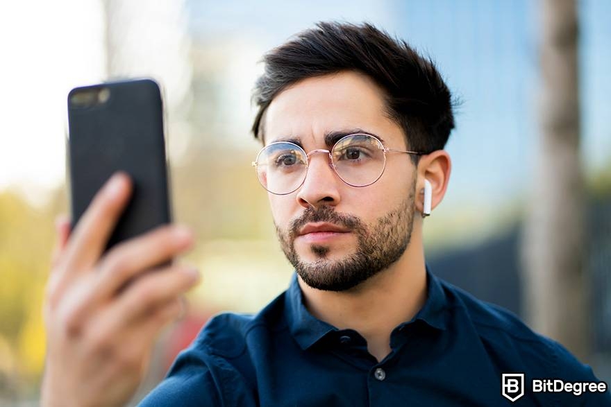 How to trade crypto: a man uses face ID verification on his phone.