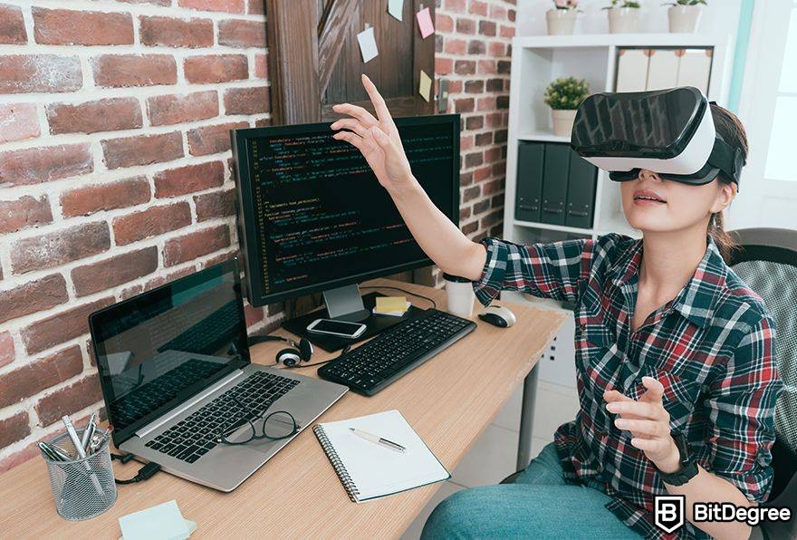 Metaverse laws: woman uses VR next to computer as she programs.