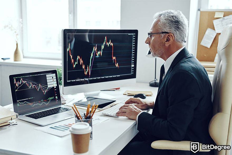 What is arbitrage trading in crypto: man watching two trading screens.