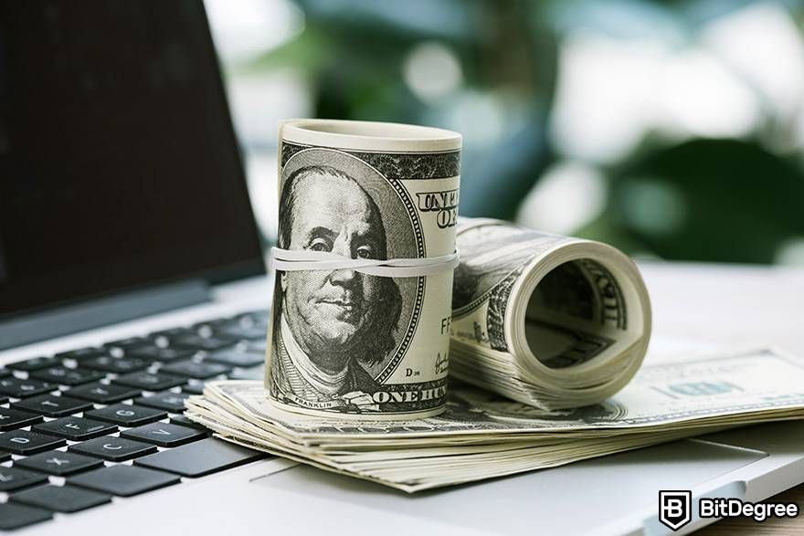 Tiền pháp định trong tiền điện tử là gì: chồng đô la Mỹ được đặt trên máy tính xách tay.