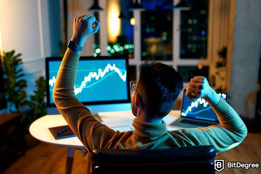 What is spot trading in crypto: a trader is observing a monitor and a laptop with market data.