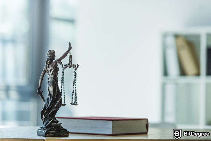 Are NFTs dead: the statue of justice next to a book on a desk.