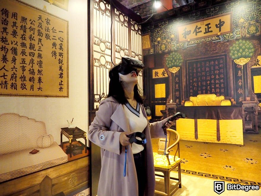 Are NFTs dead: a woman in a VR headset explores a virtual traditional Chinese room with ornate decor.