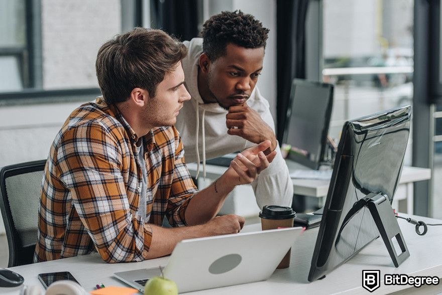 Are NFTs dead: two people looking at a computer monitor.