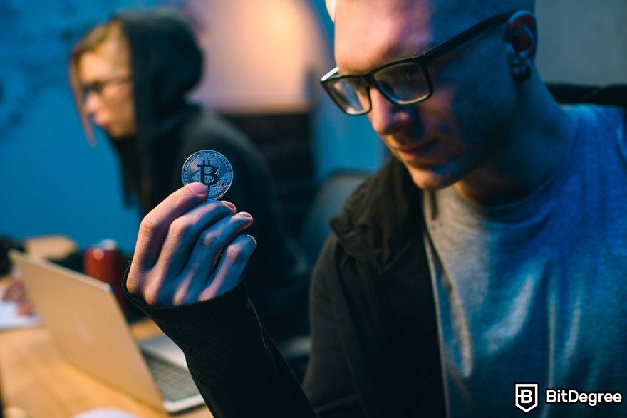 Benefits of cryptocurrency: A close-up shot of a young hacker holding Bitcoin.