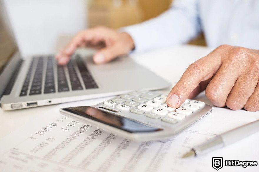 Benefits of cryptocurrency: A man doing accounting with a laptop and calculator.