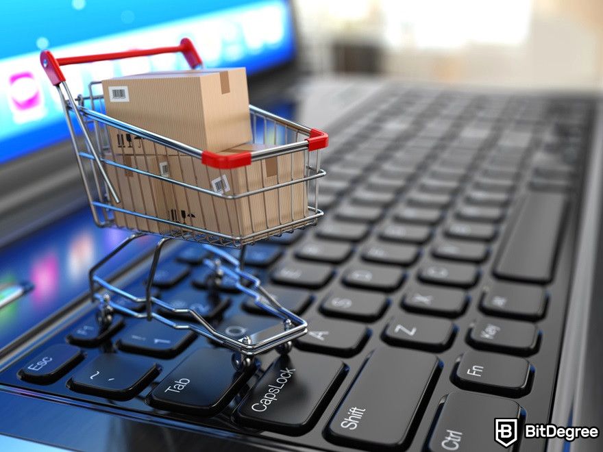 Benefits of cryptocurrency: A mini shopping cart with boxes on a laptop.