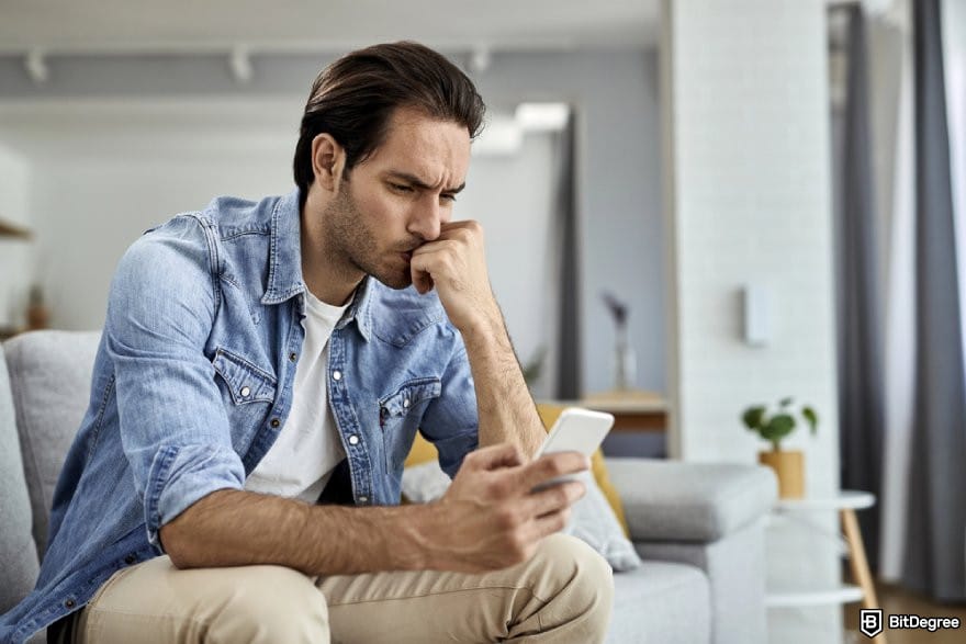 Ví Bitcoin tốt nhất: Một người sử dụng điện thoại với vẻ mặt lo lắng.