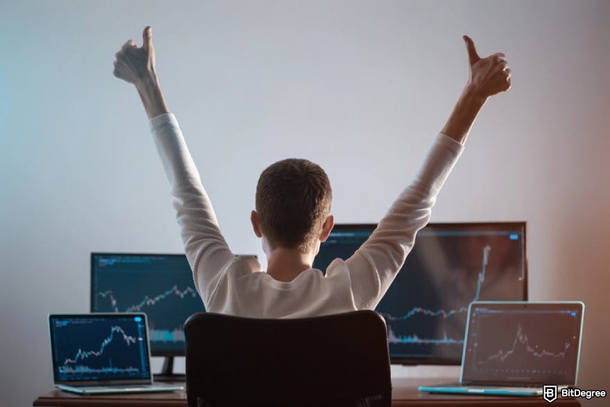 Best crypto charts: a person looking at multiple screens showing price charts while raising both arms with thumbs up.