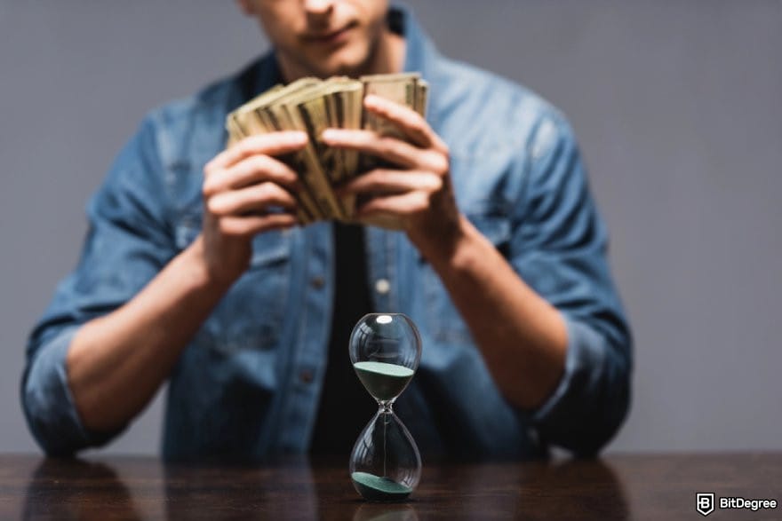 Best money transfer to India: a person counting money in front of an hourglass.
