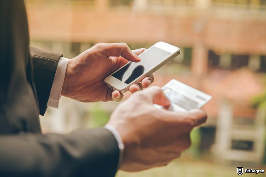 Best no-KYC crypto exchange: a man holding a phone and a credit card.
