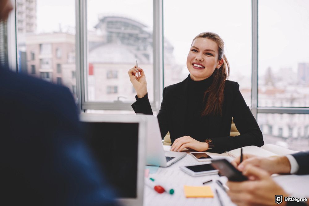 Best product management courses: a woman leads a discussion in a meeting room.