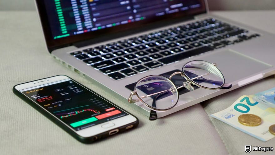 Best Sui wallet: a phone opening up Binance's trading interface, next to a pair of glasses on top of a laptop.