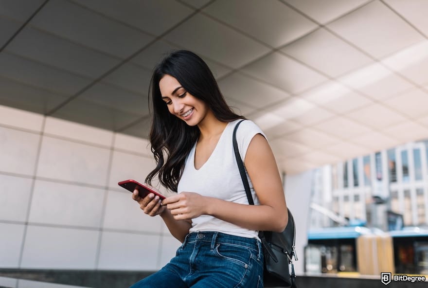 Best way to send money from India to USA: a woman smiling at her phone. Best way to send money from India to USA: a woman smiling at her phone.