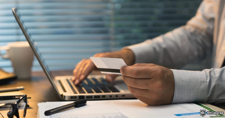 Best way to send money to Pakistan: a person holding a debit or credit card in front of a laptop.