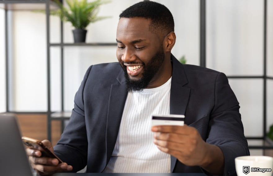 Best way to to send money to South Africa: man holding phone and card to illustrate sending money online.