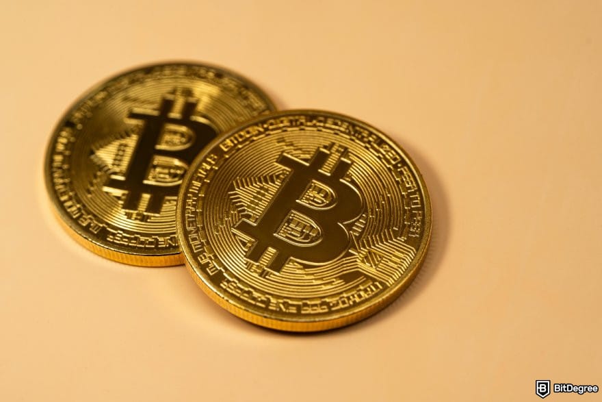 Binance review: two BTC coins on an orange surface.