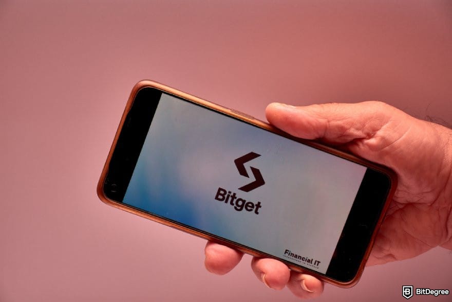 Bitget Canada: a hand holding a phone displaying Bitget logo. Bitget Canada: a hand holding a phone displaying Bitget logo.