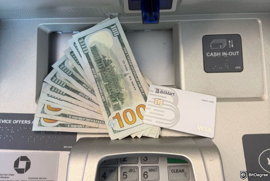 BitMart Card review: a BitMart Card laying next to US dollar bills on an ATM.