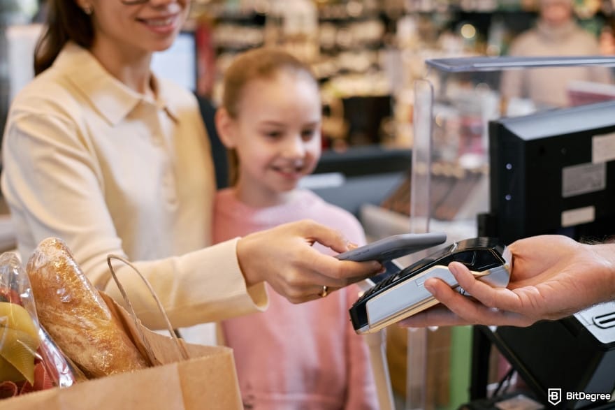 BitMart Card review: a woman making payment at store counter.