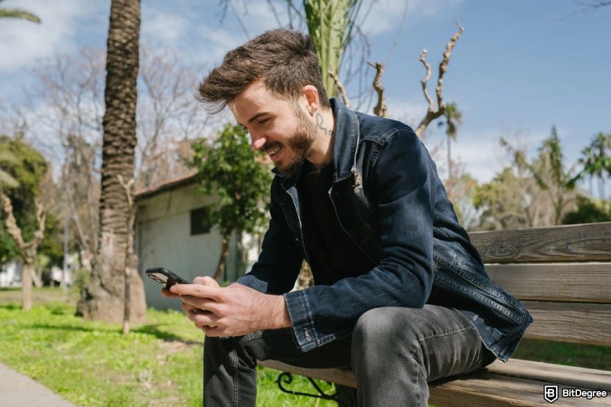 Bitsler review: a person using a phone while sitting on a bench. Bitsler review: a person using a phone while sitting on a bench.
