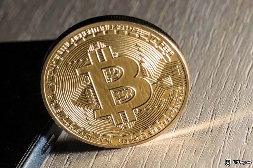 Bitsler review: a golden BTC coin beside a mobile phone. Bitsler review: a golden BTC coin beside a mobile phone.