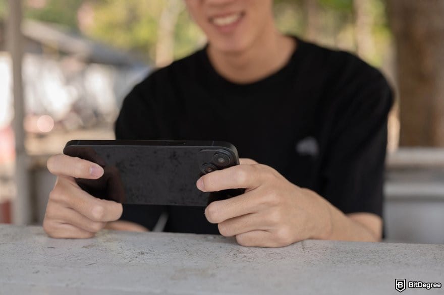 Bitsler review: a person holding a phone while smiling. Bitsler review: a person holding a phone while smiling.