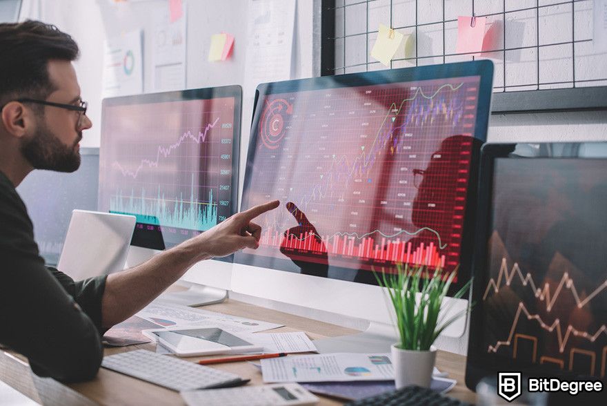 Blockchain accounting: a person pointing at a computer monitor displaying graphs of data.