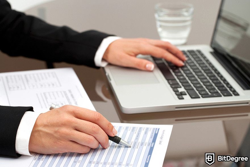 Blockchain accounting: a person reviewing documents while using a laptop.