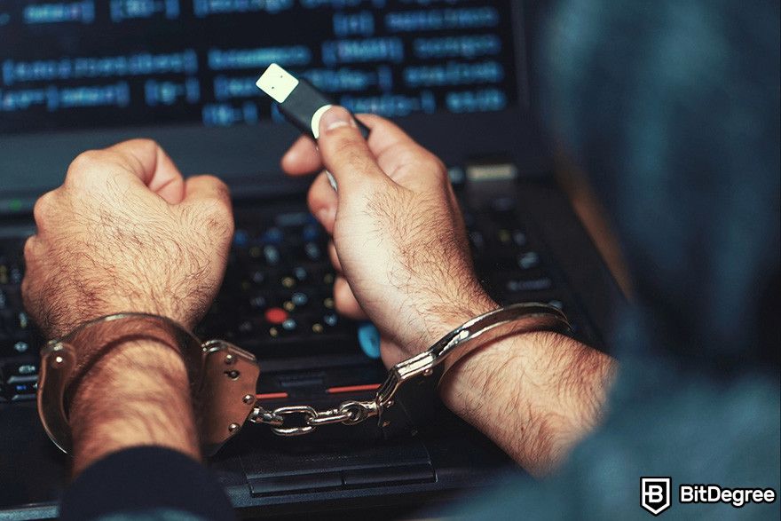 Blockchain accounting: a person in front of a laptop holding a USB flash drive while their hands being handcuffed.