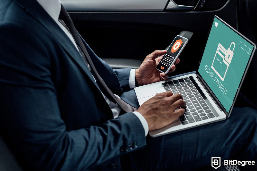 Blockchain for energy: a man in suit holding a smartphone with a laptop on his lap.