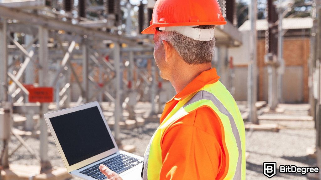 Blockchain for energy: a senior electrical technician holding a laptop.