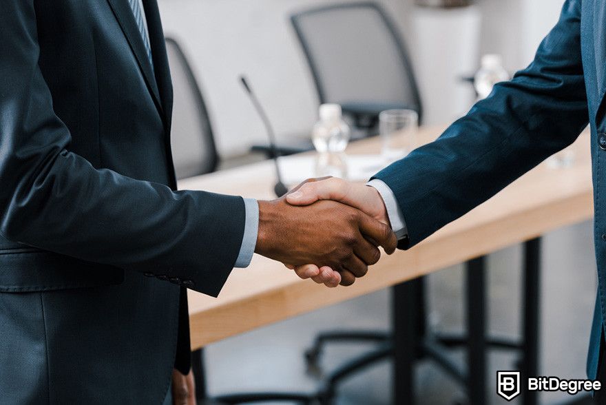 Blockchain in banking: two person in suits shaking hands.