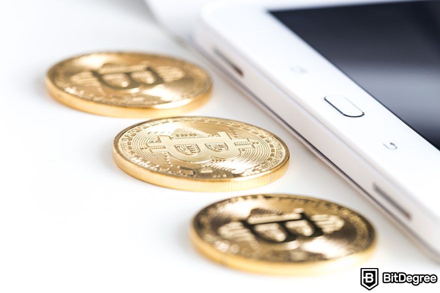 Blockchain in finance: three Bitcoin tokens besides a mobile tablet.