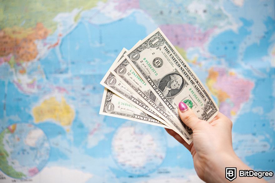 Blockchain in finance: a person holding four dollar bills in front of the world map.