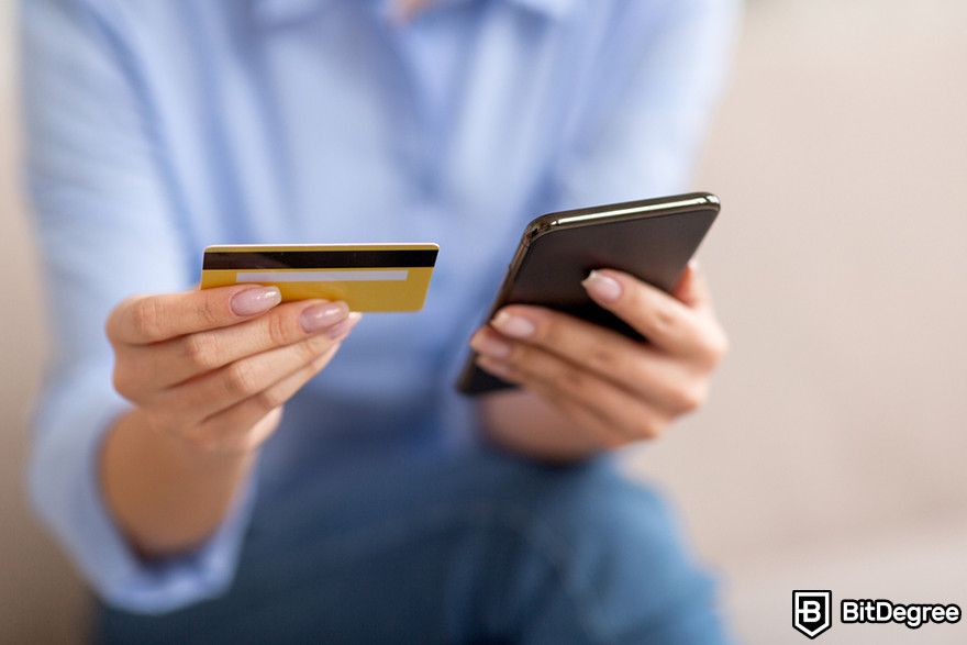 Blockchain in finance: a person holding a debit card and a mobile phone.