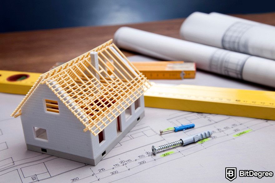 Blockchain in insurance: a miniature house model on top of a construction blueprint.