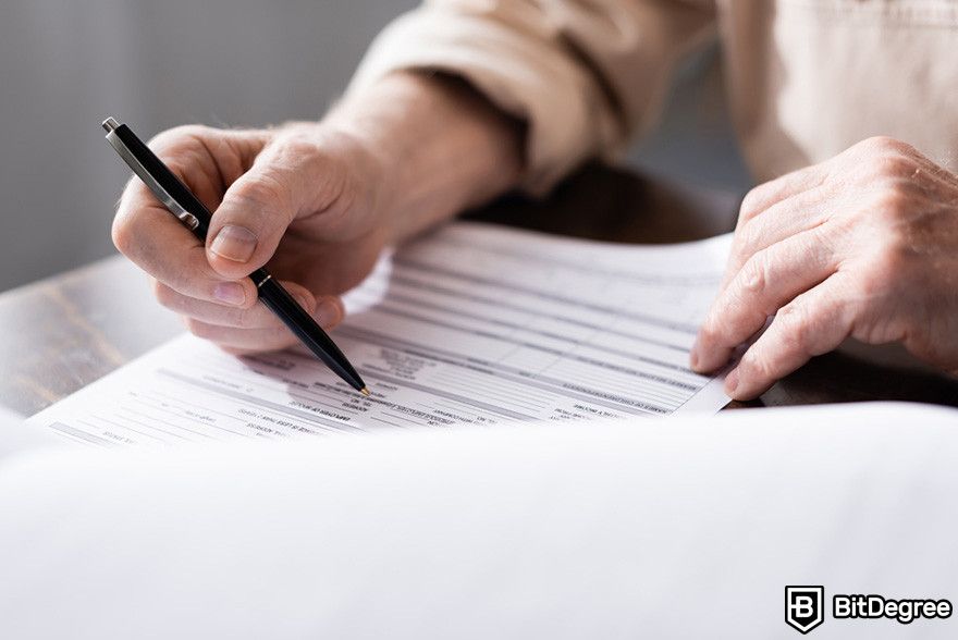 Blockchain in insurance: a person filling out forms with a pen.