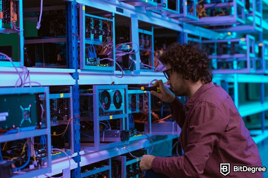 Blockchain in supply chain: Young computer engineer repairing at cryptocurrency mining farm.