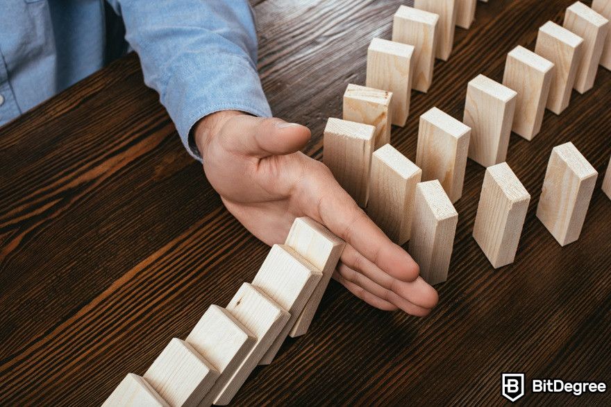 Blockchain security: A man preventing wooden blocks from falling.