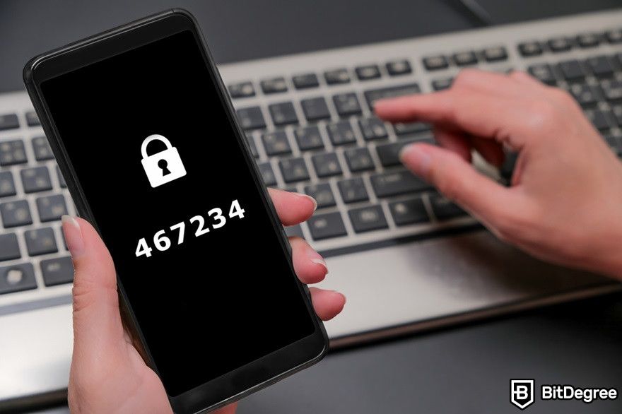 Blockchain security: A phone displaying a security code near a keyboard laptop.